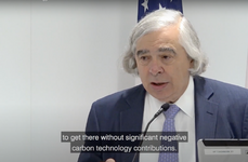 Image of Ernest Moniz speaking at a podium with the US flag behind him.